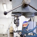 Søjleboremaskine og plastikbeholder med olie på Laboratoriet for Konstruktion